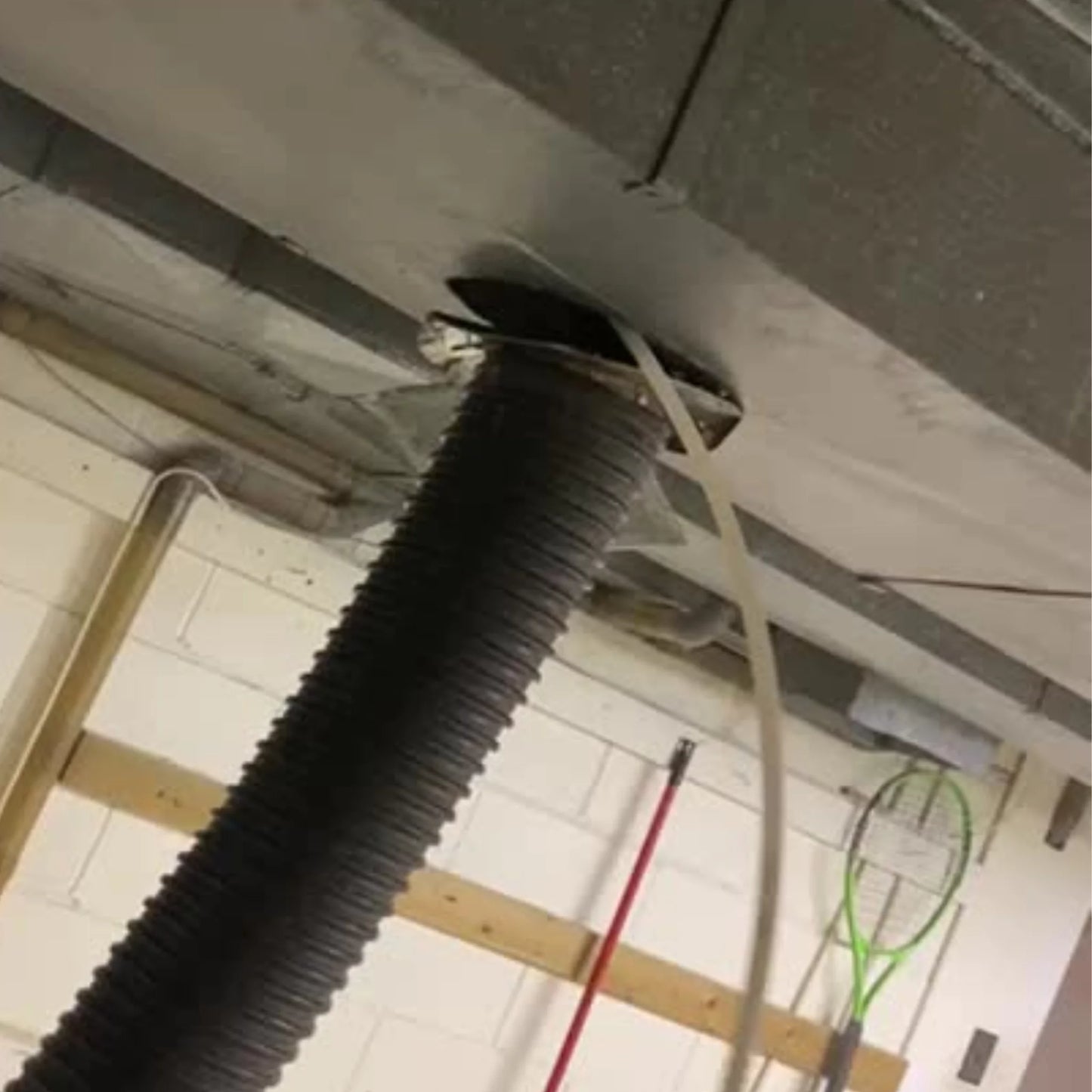 Picture showing Air duct cleaning vacuum hose connected with the main duct of a house.