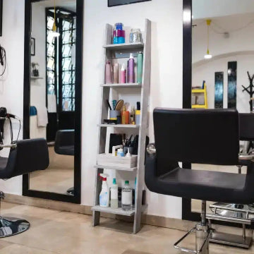 A GTA salon showcases styling chairs, a large mirror, and a ladder shelf stocked with hair products and tools. The impeccably maintained space benefits from Power HVAC Services Commercial Air Duct Cleaning of salons, ensuring a spotless environment for clients during their pampering sessions.