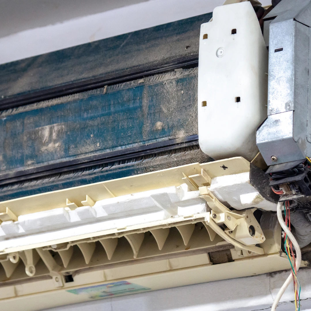 The dirty, partially disassembled AC unit with visible dust suggests the need for Power HVAC Services Residential AC Coil Cleaning in urban areas.