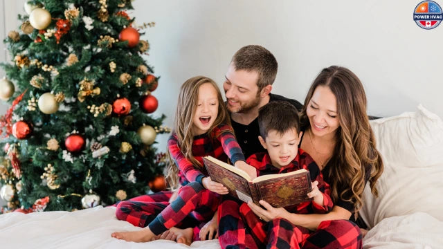 Man, woman and two kids sitting in a room besides a christmas tree. happy in reading a book and enjoying clean air due to their cleaned air ducts by Power HVAC Services.