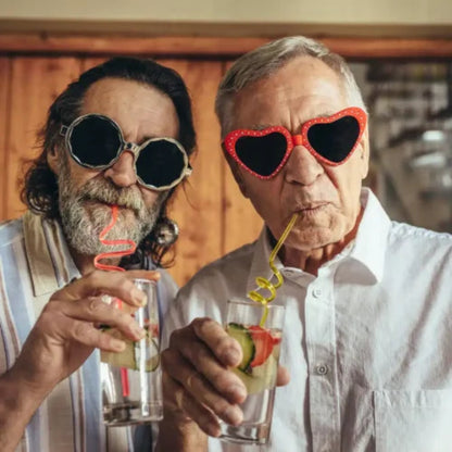 Two men sporting novelty sunglasses sip drinks with curly straws, chatting about Power HVAC Services innovative Commercial Air Duct Cleaning of retirement homes in the GTA.