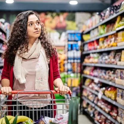 A lady with curly hair and a scarf pushes a shopping cart through a GTA grocery store aisle, looks happy to see professionally cleaned air ducts of super store by Power HVAC Services.